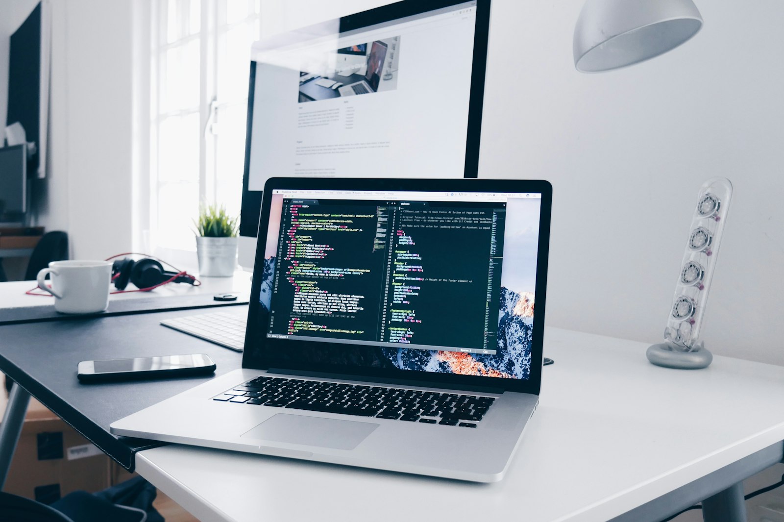 Laptop on a desk with code on screen — comparing software options